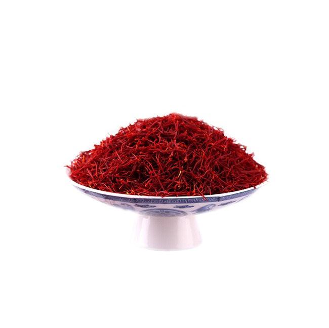 Pile of vibrant red saffron threads on a decorative white and blue pedestal plate