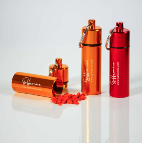 Orange and red Saffronice branded metal containers with red saffron threads spilled from one container