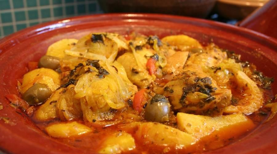 Moroccan chicken tagine with potatoes, olives, onions, and spices in a traditional earthenware dish