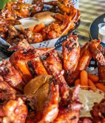 Buffet of saffron Memphis chicken wings with sweet potato fries, carrot sticks, and creamy dipping sauces