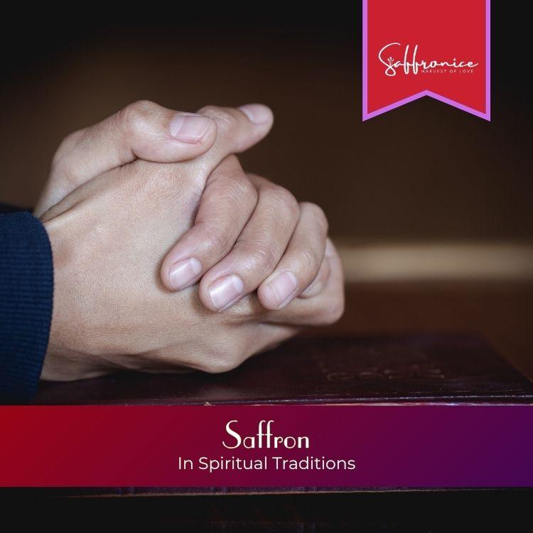 Hands clasped in prayer resting on a book with text about saffron in spiritual traditions