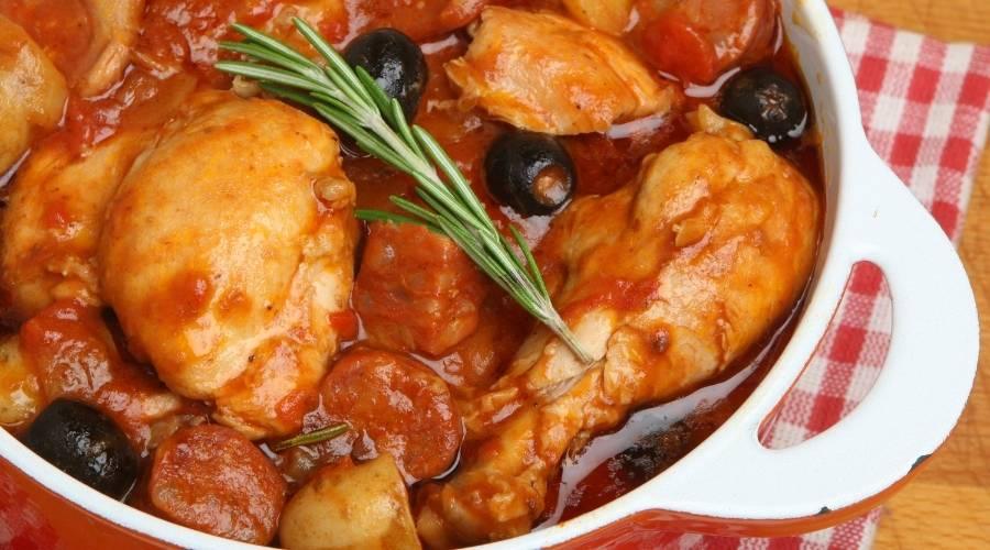 Spanish chicken stew with chorizo, black olives, potatoes, and rosemary in white casserole