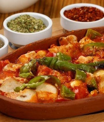 Traditional Ethiopian doro wat stew with chicken and green chili served in a clay pot with spices in white bowls