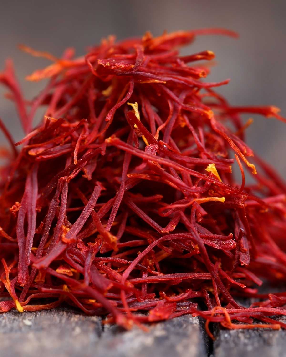 Close-up of vibrant red saffron threads on wooden surface, highlighting spice texture